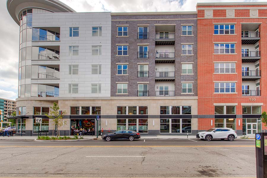 Exterior view of high-rise Penrose On Mass Apartments with cars parked in front.